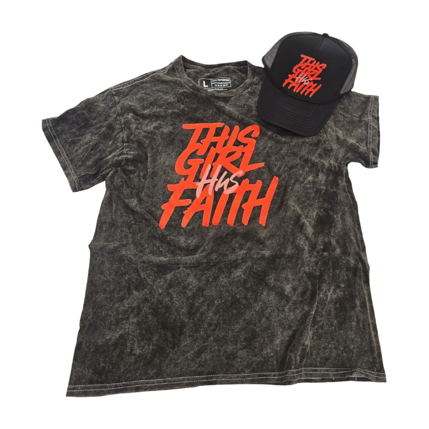 Black mineral wash short-sleeve T-shirt with red text reading ‘This Girl Has Faith,’ displayed flat with a matching black trucker hat featuring the same red lettering.