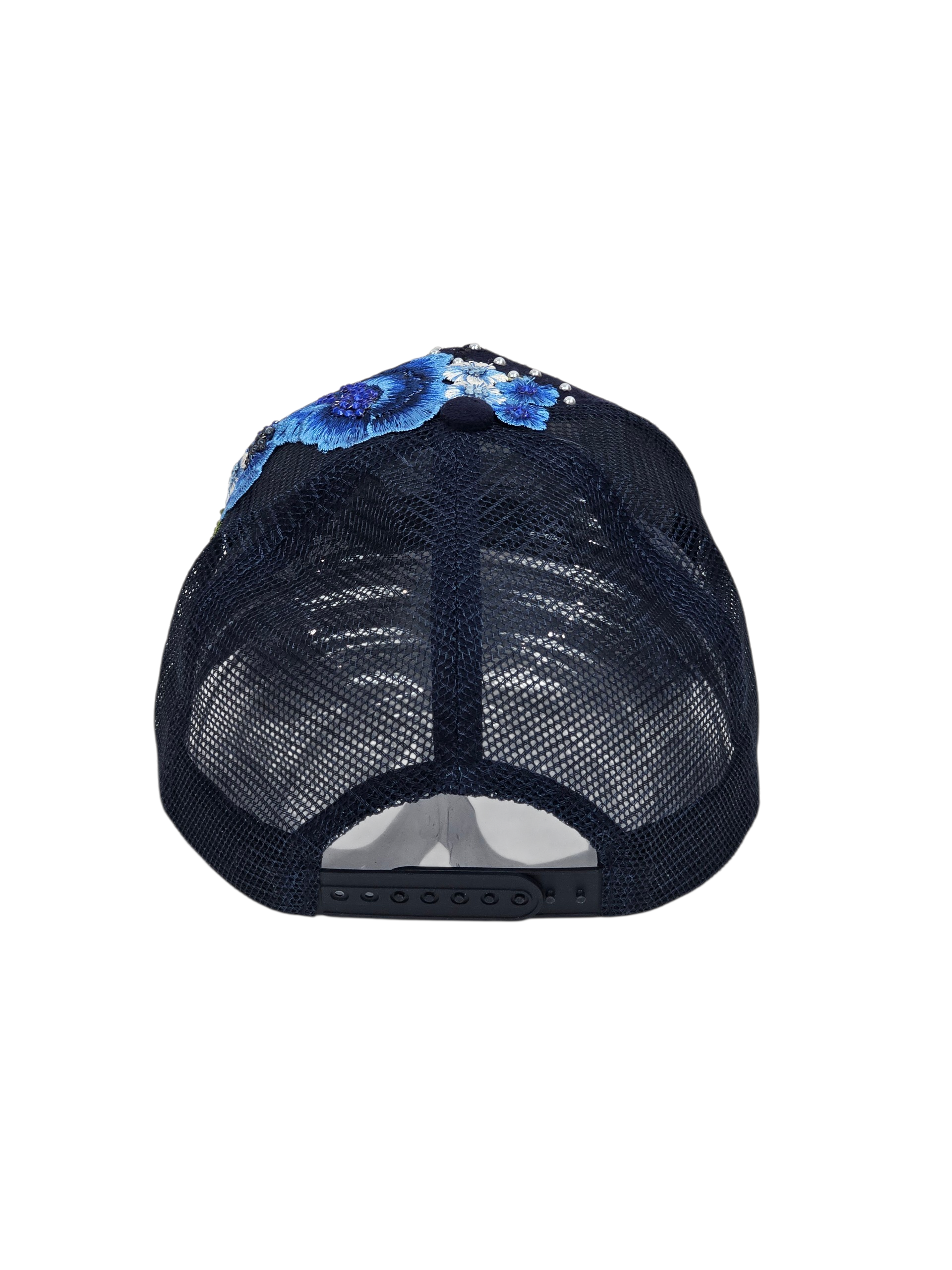 A rear view of a dark navy blue trucker hat with a blue and white floral pattern on the back panel, set against a plain white background.