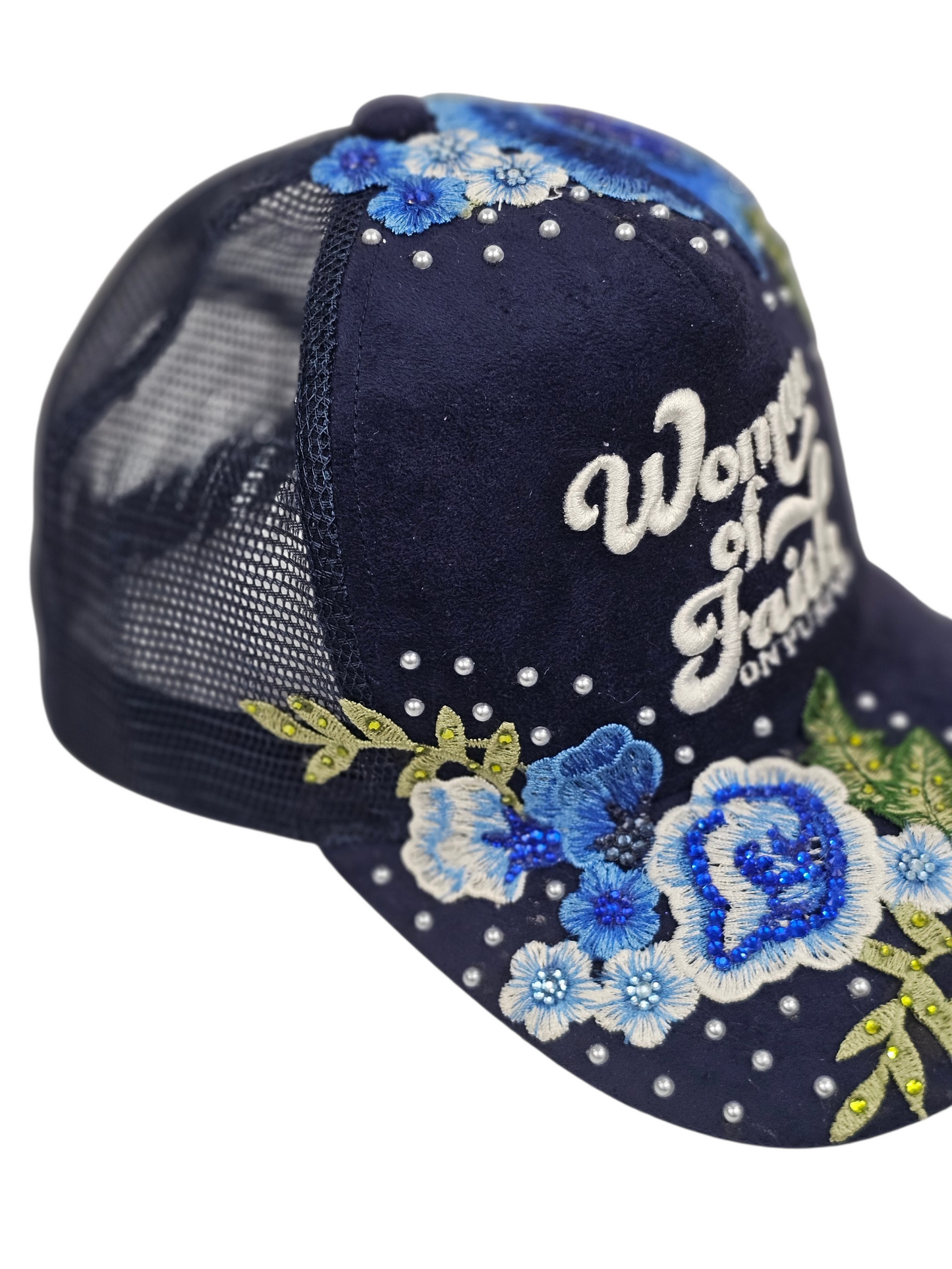 A navy blue trucker hat with embroidered blue and white flowers, green leaves, and white rhinestones. The front panel features white embroidered text reading 'Word of Faith'.